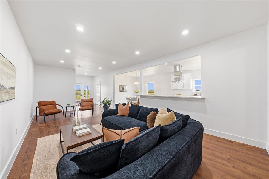 Open-concept living space featuring wood-finish flooring, recessed lighting, and white walls