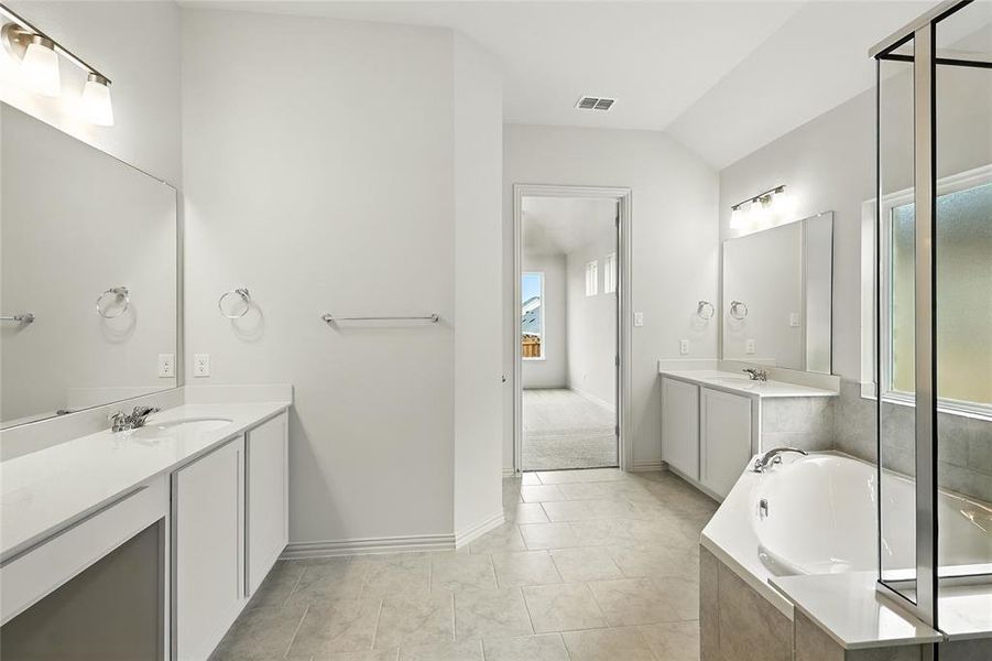 Full bathroom with two vanities, a bath, light tile patterned flooring, and lofted ceiling Full bathroom with two vanities, a bath, light tile patterned flooring, and lofted ceiling