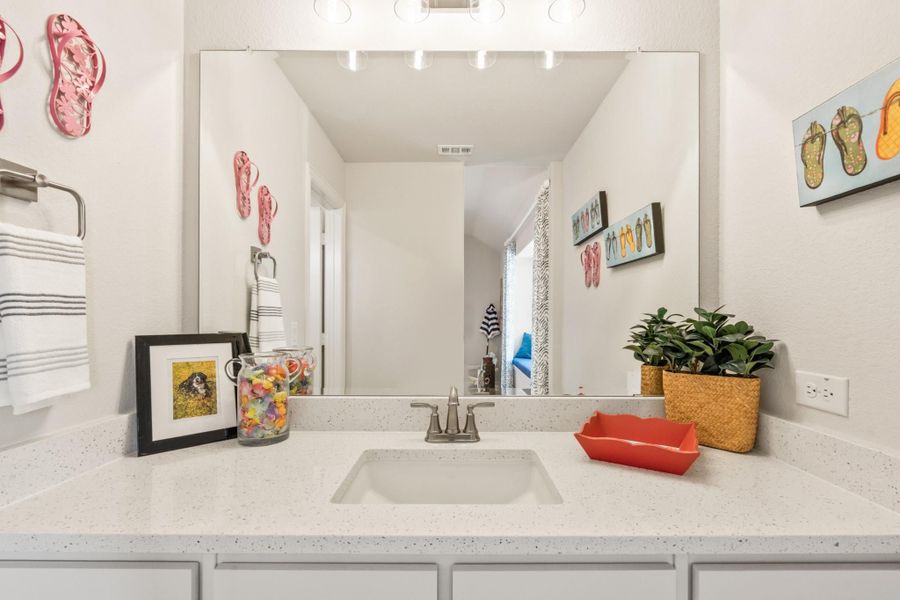 Bathroom vanity with white quartz countertop, undermount sink, large mirror, and colorful flip-flop wall decor Bathroom vanity with white quartz countertop, undermount sink, large mirror, and colorful flip-flop wall decor