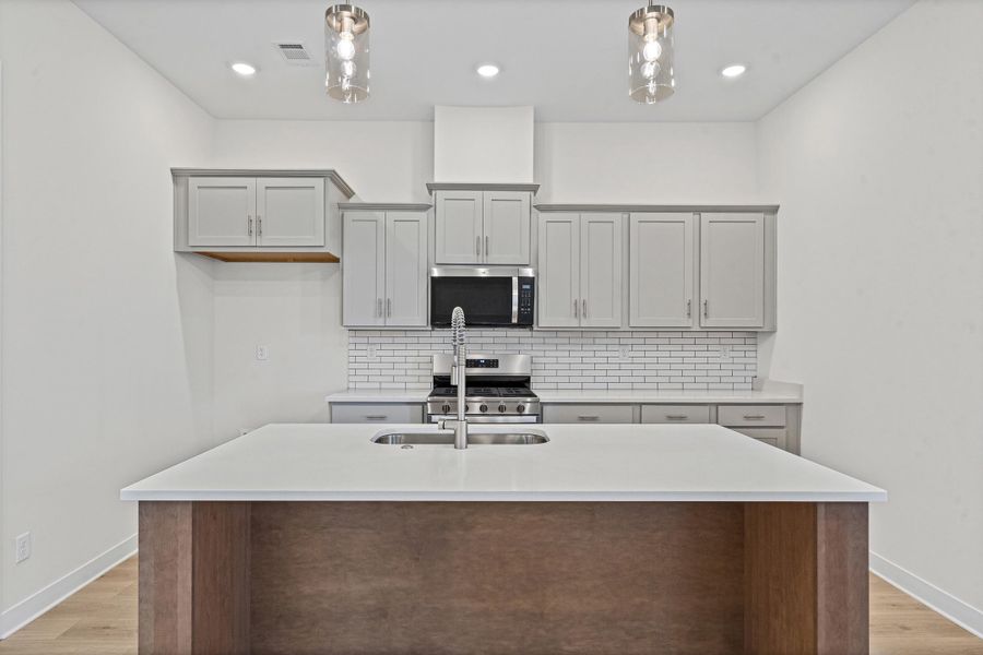 Kitchen featuring a central island with an undermount sink, light countertops, and wood-finish paneling Kitchen featuring a central island with an undermount sink, light countertops, and wood-finish paneling