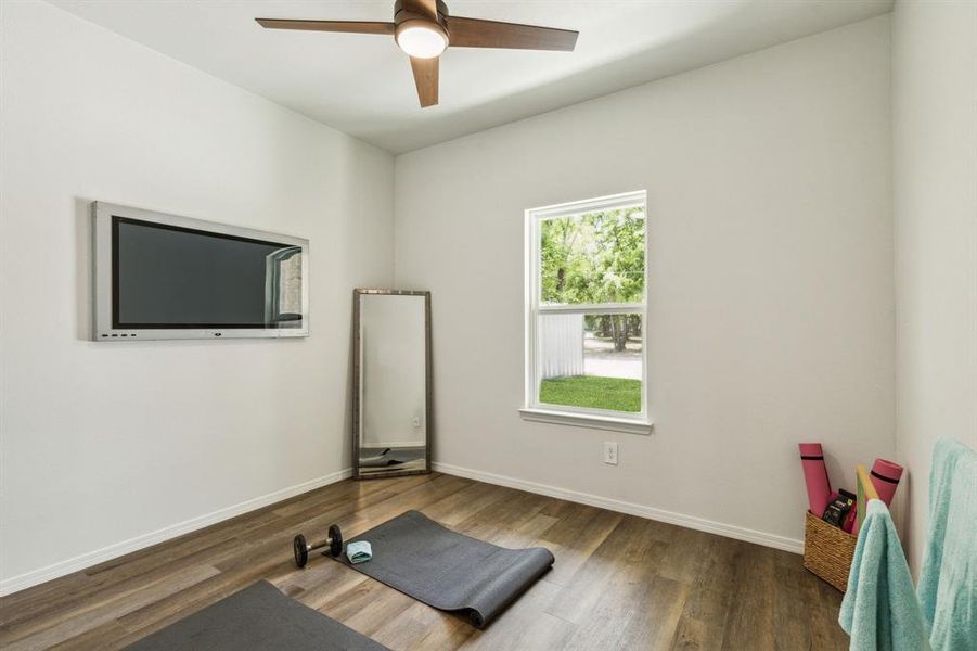 Exercise room with ceiling fan and dark hardwood / wood-style flooring