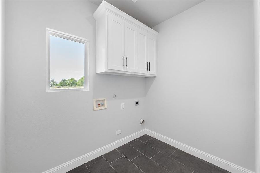 Clothes washing area with hookup for an electric dryer, hookup for a gas dryer, hookup for a washing machine, baseboards, and cabinet space