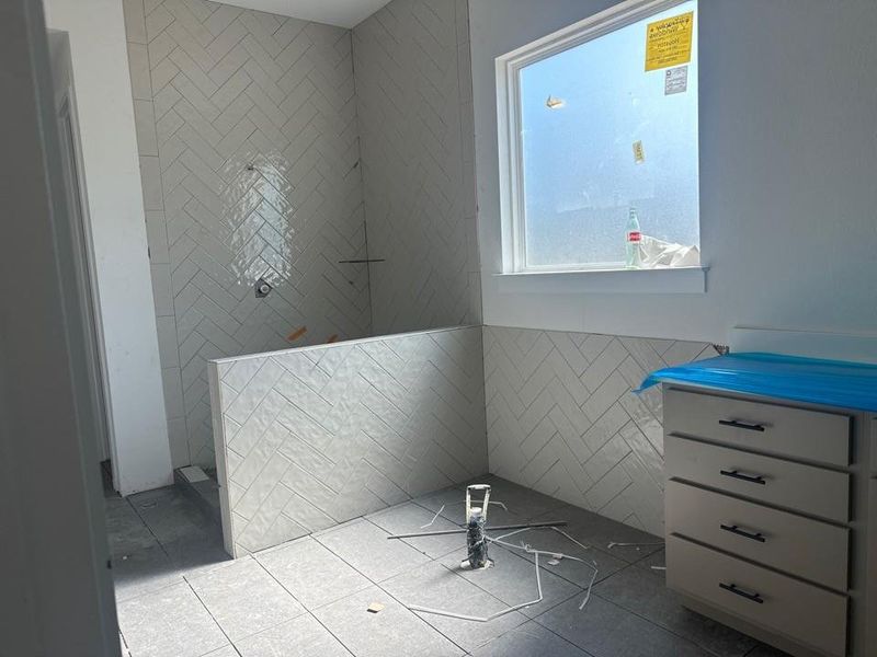 Full bath featuring tile walls, walk in shower, and tile patterned flooring