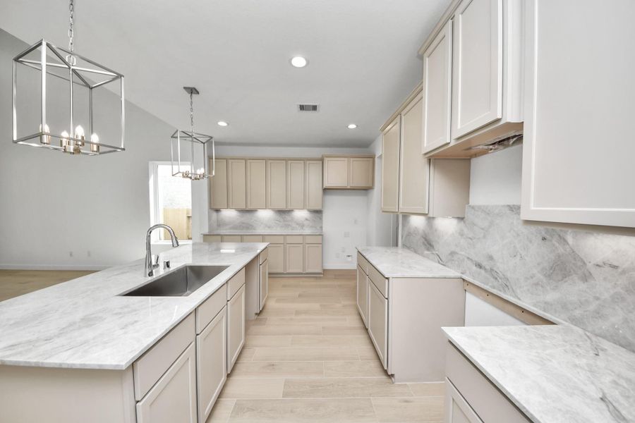 The kitchen is a culinary haven, featuring granite countertops, a tile backsplash, stainless steel appliances, 42” upper cabinets, and undercabinet lighting. Sample photo of completed home with similar floor plan. Actual colors and selections may vary.
