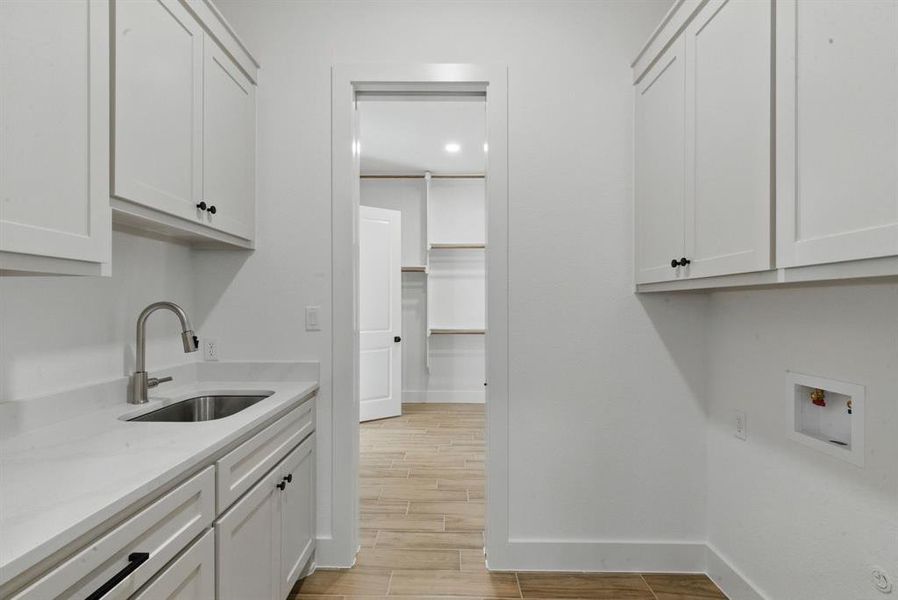 Washroom with cabinet space, wood finish floors, and hookup for a washing machine Washroom with cabinet space, wood finish floors, and hookup for a washing machine