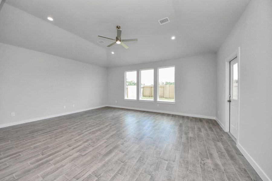 Welcome family and guests to your charming living room! With its high ceilings, recessed lighting, ceiling fan, custom paint, beautiful flooring, and large windows that let in abundant natural light, this room is perfect for gatherings. Sample photo of completed home with similar floor plan. Actual colors and selections may vary.