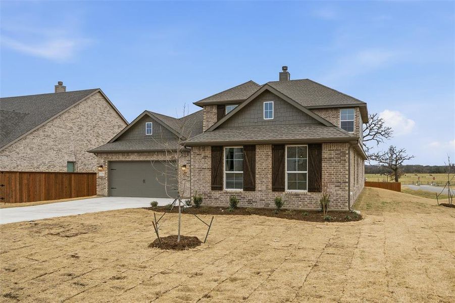 Craftsman-style house with driveway, roof with shingles, a chimney, a garage, and brick siding