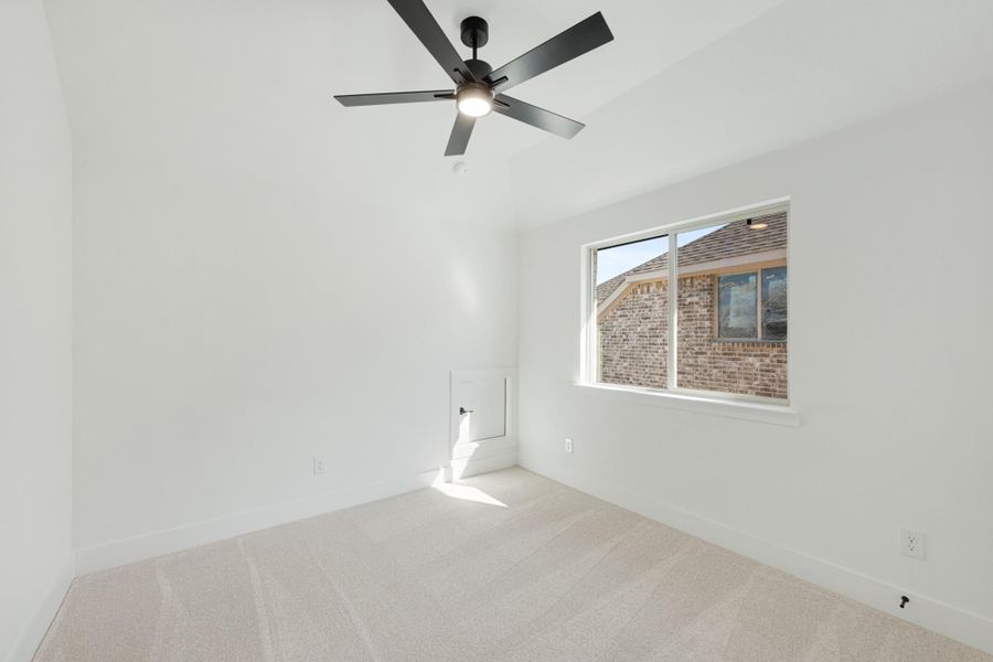 Empty bedroom with white walls, carpet flooring, ceiling fan, and single window