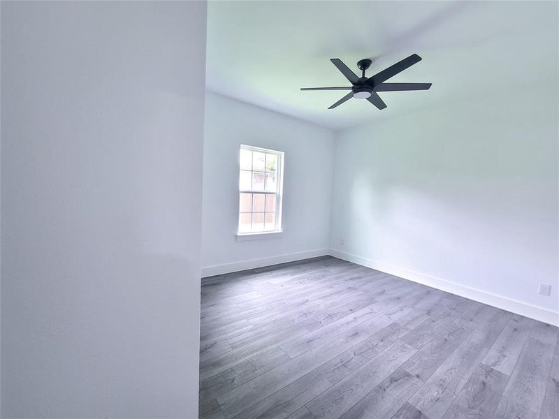 Empty room with wood finished floors and a ceiling fan Empty room with wood finished floors and a ceiling fan