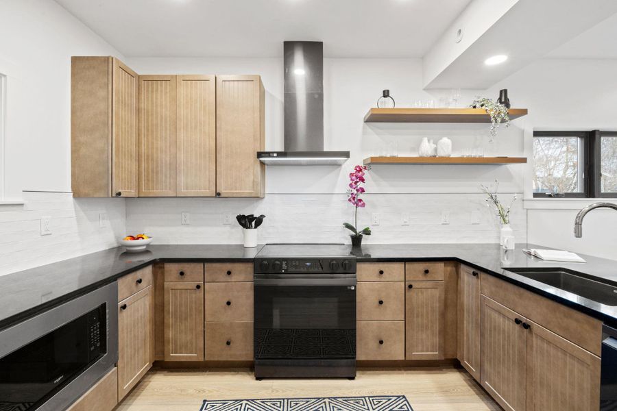 Kitchen with electric range, a sink, backsplash, wall chimney range hood, and built in microwave