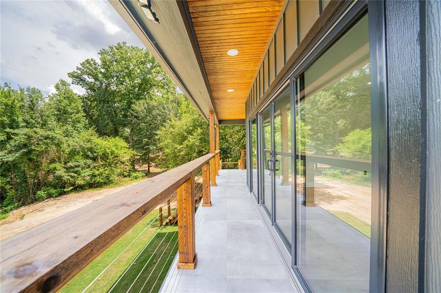 Covered outdoor living space featuring a wood-finish ceiling with recessed lighting, large format tile flooring, and multiple sliding glass doors