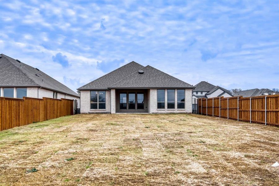 Back of house with a fenced backyard, a patio, a shingled roof, and brick siding