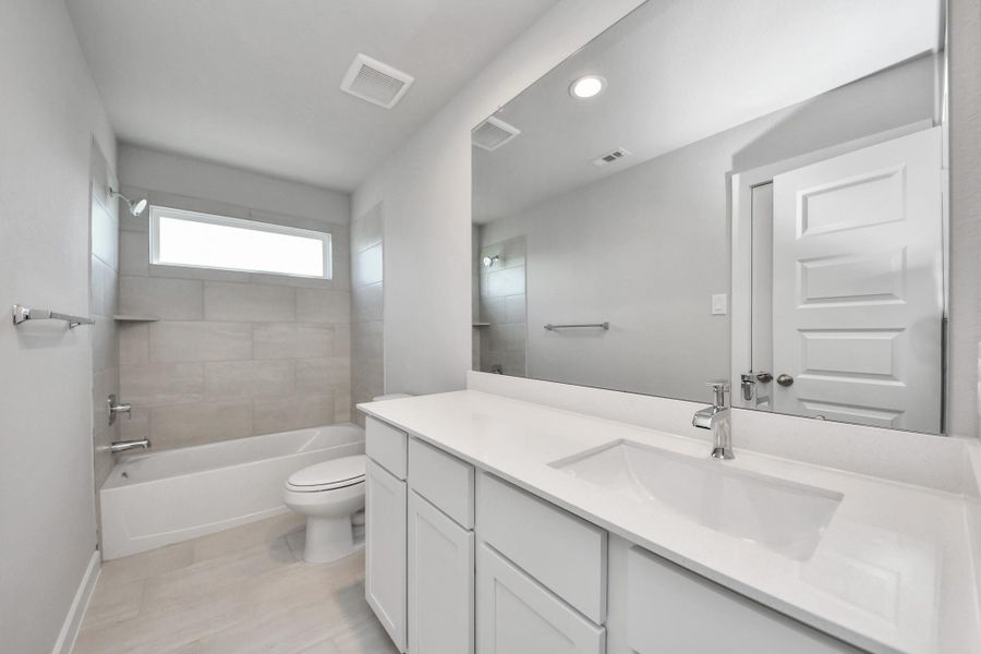 Secondary bath features tile flooring, bath/shower combo with tile surround, light stained wood cabinets, beautiful light countertop. Sample photo of completed home with similar floor plan. Actual colors and selections may vary. Secondary bath features tile flooring, bath/shower combo with tile surround, light stained wood cabinets, beautiful light countertop. Sample photo of completed home with similar floor plan. Actual colors and selections may vary.