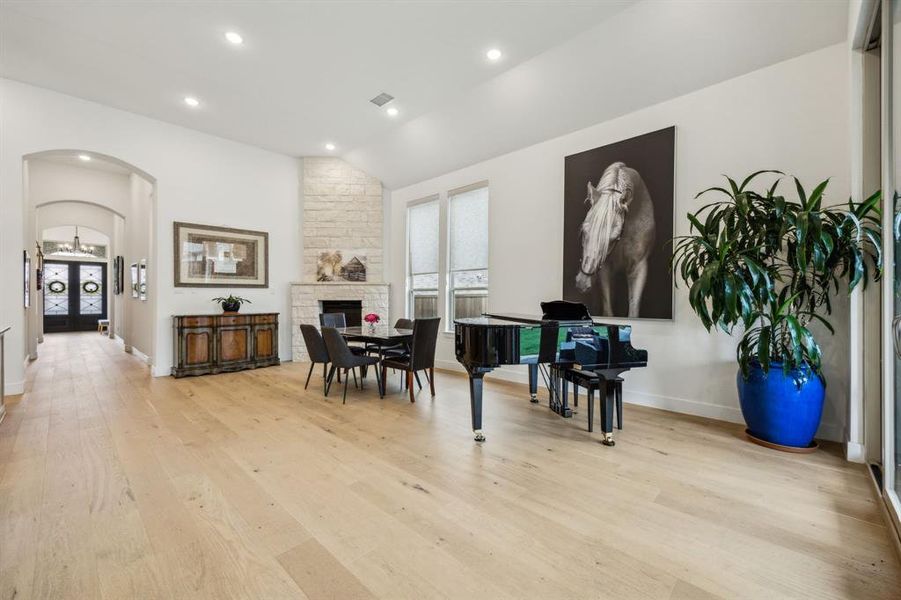 Dining room featuring arched walkways, light wood-style floors, vaulted ceiling, recessed lighting, and baseboards