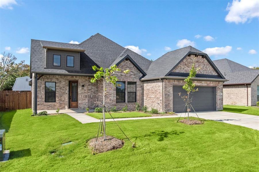 View of front of property with a shingled roof, concrete driveway, brick siding, and an attached garage