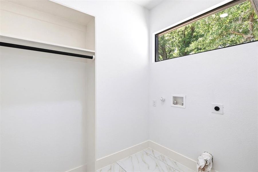 Utility space featuring a horizontal window, white walls, and wood-finish tile flooring