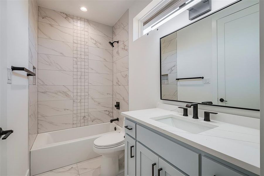 Full bathroom with tiled shower / bath combo, toilet, and vanity