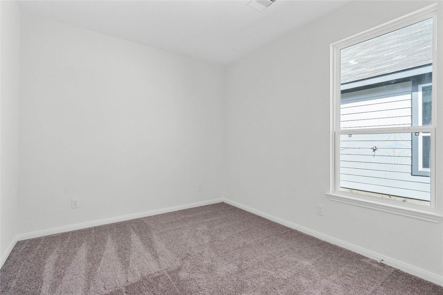 A bright and spacious secondary bedroom, with plush carpeting, large window and ample closet space, offers a comfortable retreat for family or guests.