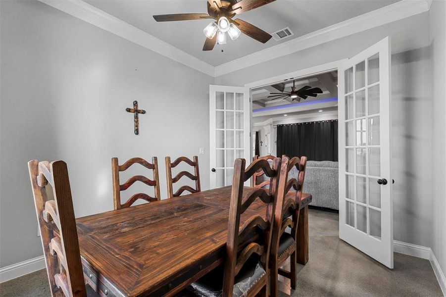 Dining space with ornamental molding, french doors, coffered ceiling, and ceiling fan