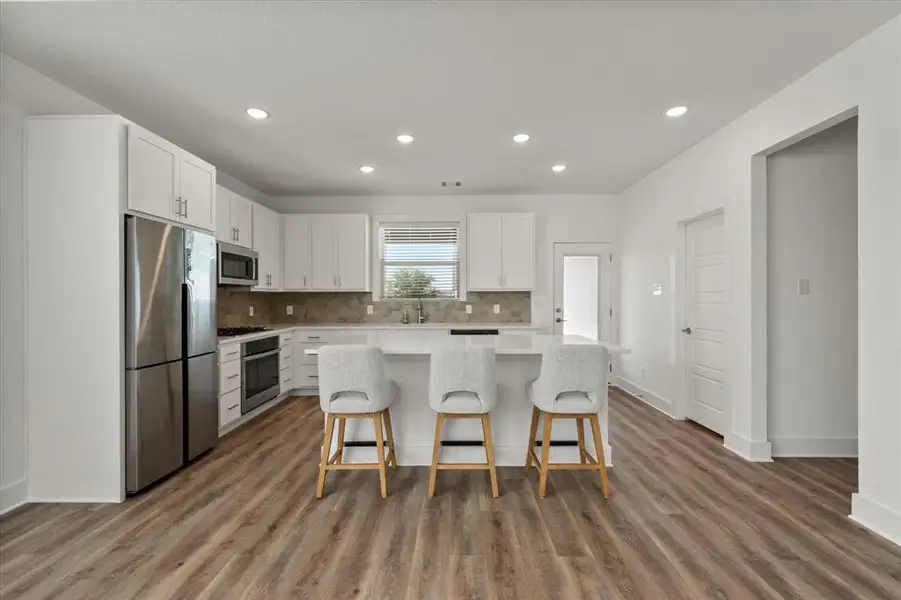 Kitchen features appliances with stainless steel finishes, a breakfast bar, granite countertops, beautiful white cabinetry and a large walk-in Pantry!