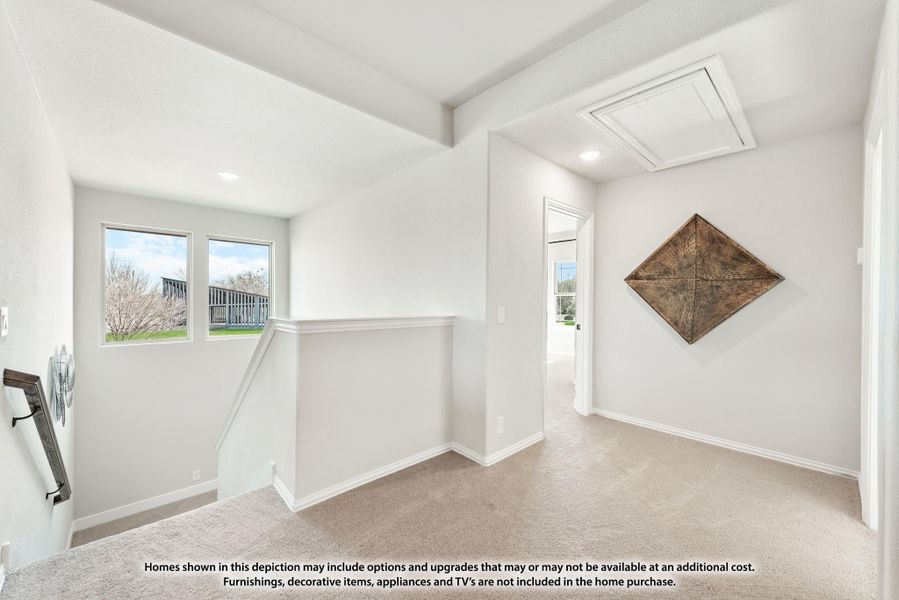 Upstairs hallway with carpet flooring, staircase landing, white walls, and attic access panel in ceiling