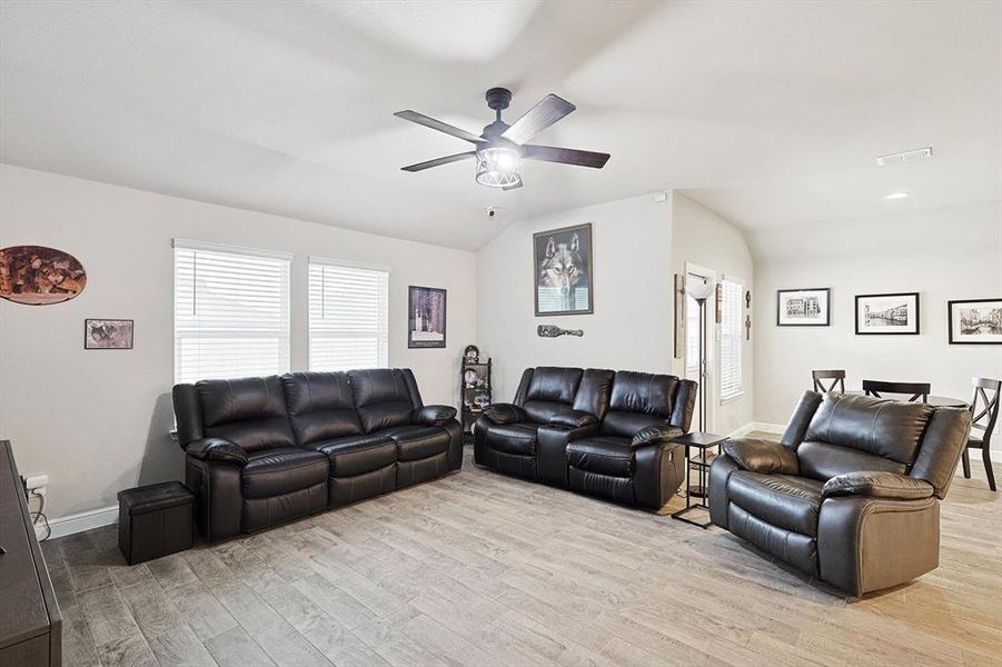Living room featuring lofted ceiling, light wood-style flooring, and a wealth of natural light