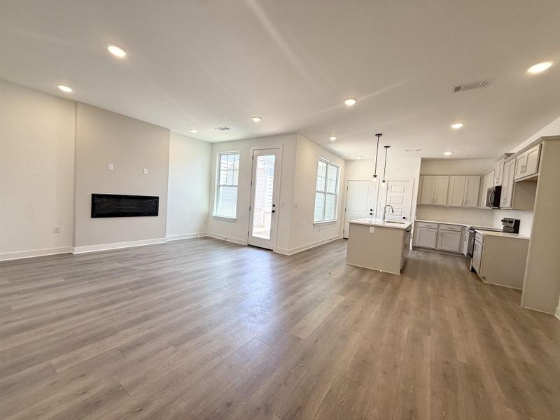 Unfurnished living room featuring recessed lighting, light wood-style floors, and a glass covered fireplace