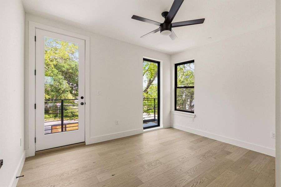 Bright interior space featuring a glass-paneled door opening to an outdoor balcony with black metal railings