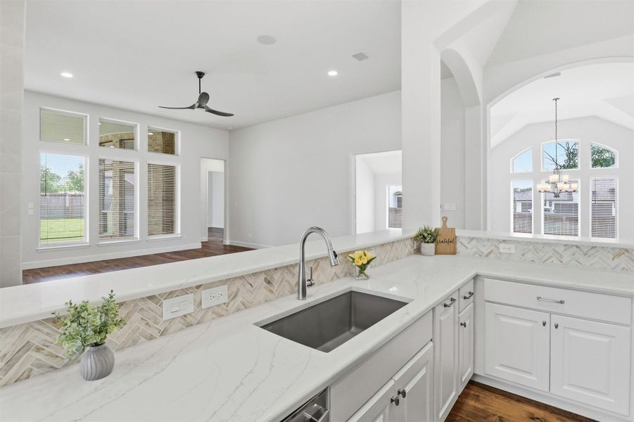 The oversized upgraded granite sealed sink sits perfectly positioned overlooking the open living room. Soaring ceilings with natural light pouring in from every angle. The arched window, warm hardwood floors, stunning view of outdoors visible from the kitchen remind you, this home was designed for real life, lived beautifully.