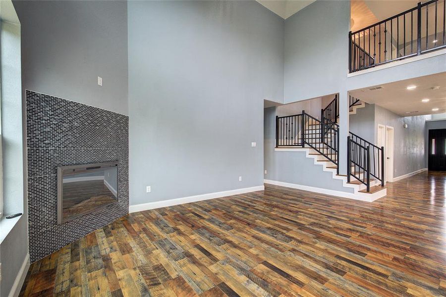 Unfurnished living room featuring a fireplace, hardwood / wood-style flooring, and a towering ceiling