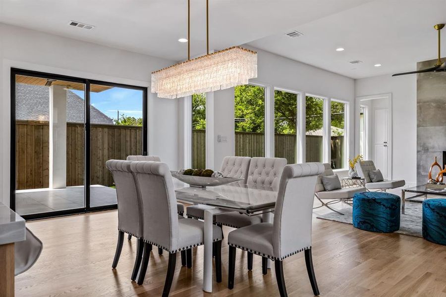 Dining space featuring ceiling fan with notable chandelier, a healthy amount of sunlight, and light wood-type flooring