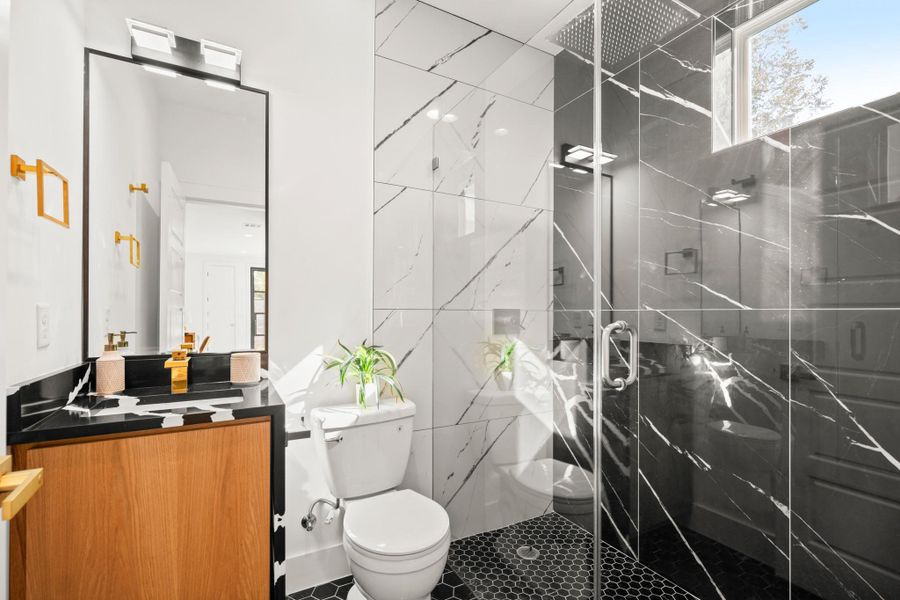 Bathroom with vanity, a marble finish shower, tile walls, and tile patterned floors Bathroom with vanity, a marble finish shower, tile walls, and tile patterned floors