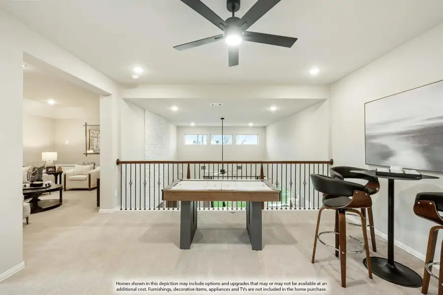 Loft game room with air hockey table, bar seating, ceiling fan, and open railing overlooking lower level