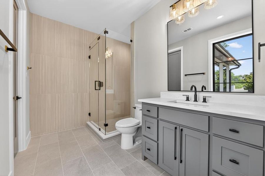 Contemporary bathroom featuring a spacious glass-enclosed shower, a gray vanity with a white countertop, and modern black hardware Contemporary bathroom featuring a spacious glass-enclosed shower, a gray vanity with a white countertop, and modern black hardware
