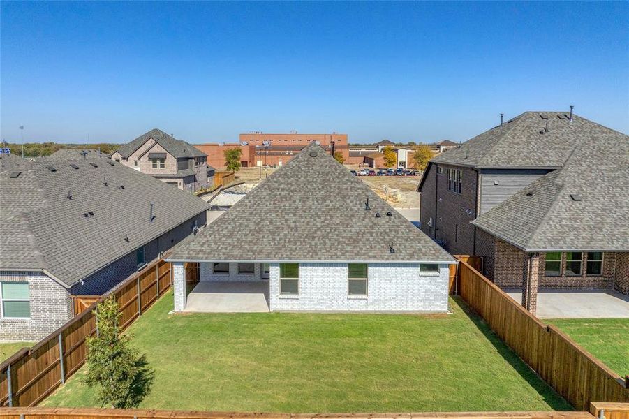 Back of property featuring a patio area, roof with shingles, a residential view, and brick siding