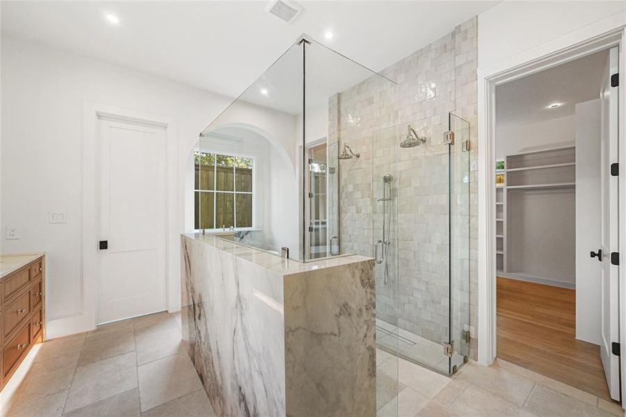 Luxury bathroom featuring a glass-enclosed shower with dual showerheads and subway tile surround