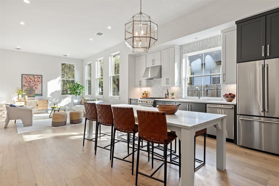 Kitchen with a kitchen breakfast bar, premium appliances, pendant lighting, backsplash, and a kitchen island