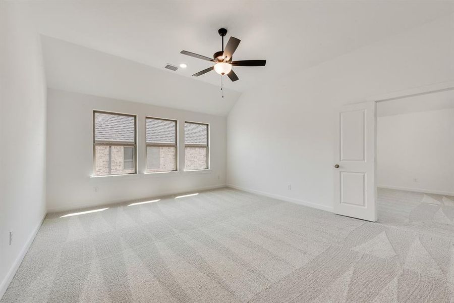 Empty room featuring light carpet, vaulted ceiling, and ceiling fan Empty room featuring light carpet, vaulted ceiling, and ceiling fan