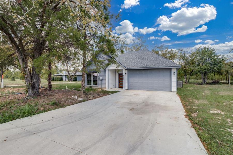 View of front of property with driveway, a shingled roof, an attached garage, and a front yard View of front of property with driveway, a shingled roof, an attached garage, and a front yard