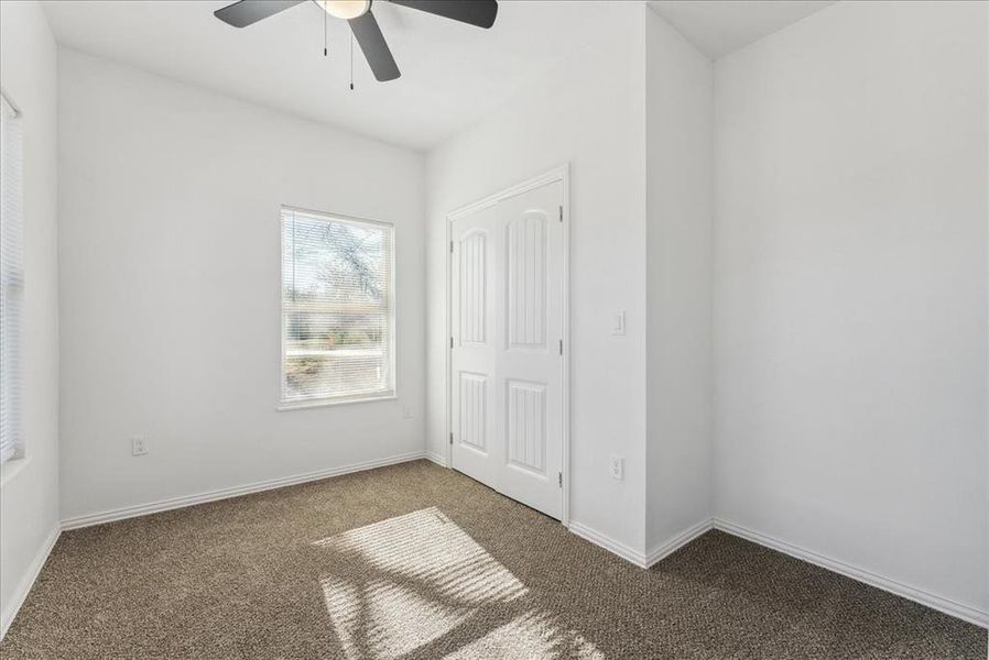 Unfurnished bedroom featuring carpet, a closet, baseboards, and a ceiling fan