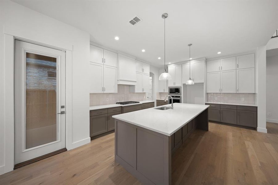 Kitchen featuring white cabinetry, pendant lighting, a kitchen island with sink, light wood-style flooring, and recessed lighting