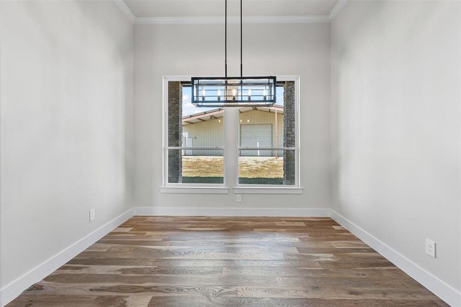 Unfurnished dining area featuring ornamental molding and dark wood-style floors