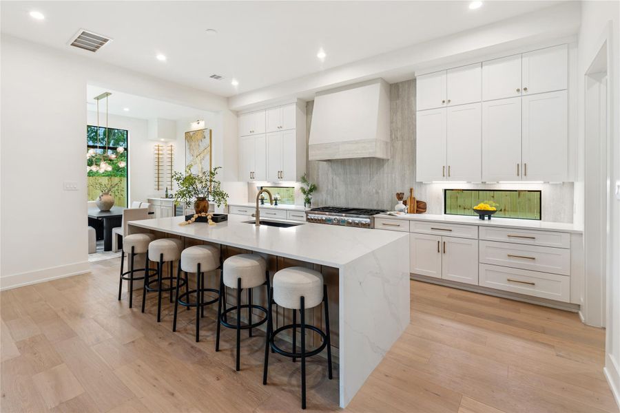 Luxurious kitchen combines premium Thermador appliances with brilliant design elements, including transom windows beneath the upper cabinetry that maximize natural light while preserving full cabinet height. The result is a bright, airy workspace with abundant storage.