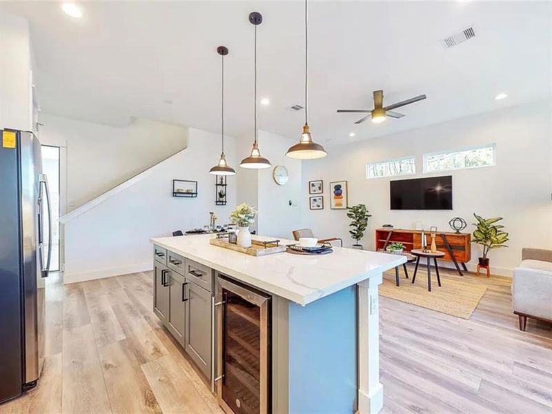 The kitchen is bright and airy, with large windows that let in plenty of natural light. The room is decorated with a few plants and other decorative items, creating a warm and inviting atmosphere. The kitchen is well-equipped, with a microwave, oven, and dishwasher. The overall design of the kitchen is modern and minimalist, with a focus on functionality and clean lines.