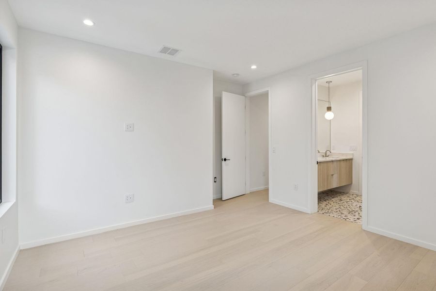 Bedroom #3 with light wood finished floors, recessed lighting, and ensuite bath