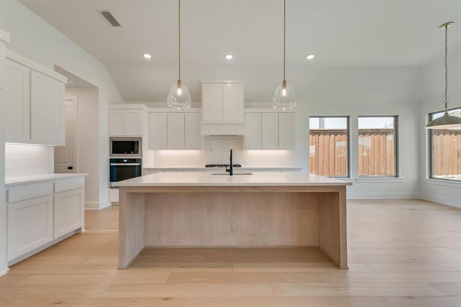Kitchen featuring backsplash, stainless steel appliances, white cabinets, light wood-style flooring, and recessed lighting