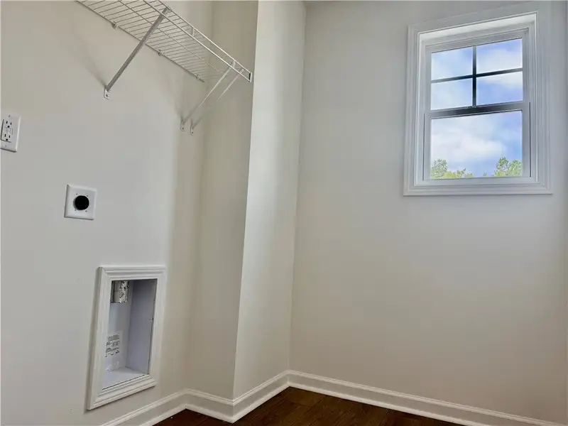 A compact laundry space features dark wood floorin