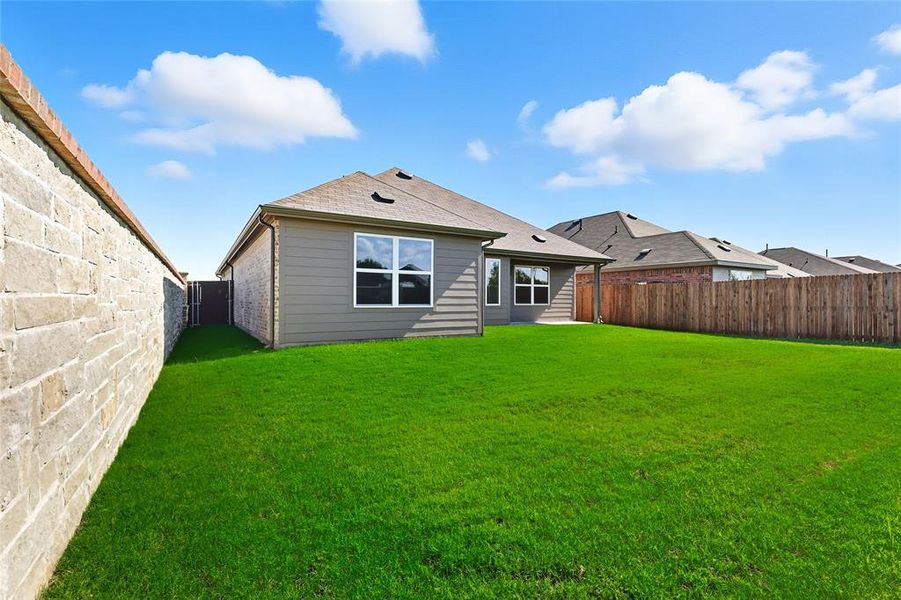 Back of house featuring a fenced backyard and roof with shingles