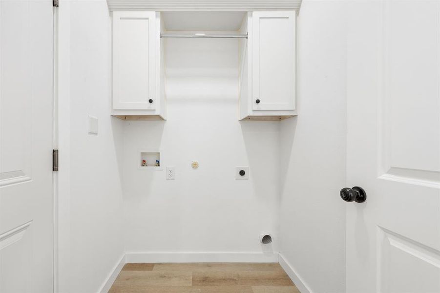 Laundry room featuring hookup for a gas dryer, cabinets, hookup for an electric dryer, light wood-type flooring, and washer hookup