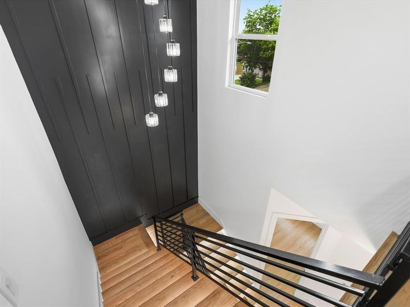 Staircase with wood-finish treads, black metal railing, and a vertical paneled accent wall
